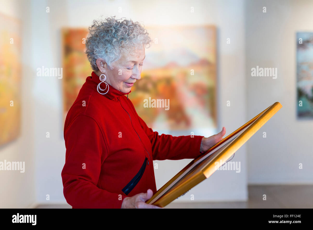 Ältere Mischlinge-Frau mit Bild in Kunstgalerie Stockfoto
