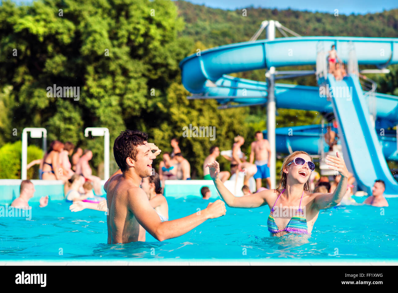 Junges Paar im Schwimmbad an sonnigen Tag. Wasserrutsche. Stockfoto Junges Paar im Schwimmbad an sonnigen Tag. Wasserrutsche. Stockfoto