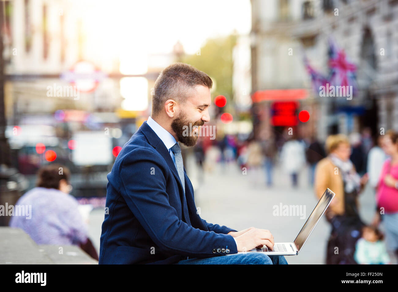 Hipster-Manager arbeiten am Laptop an sonnigen Piccadilly Circus, Lo Stockfoto