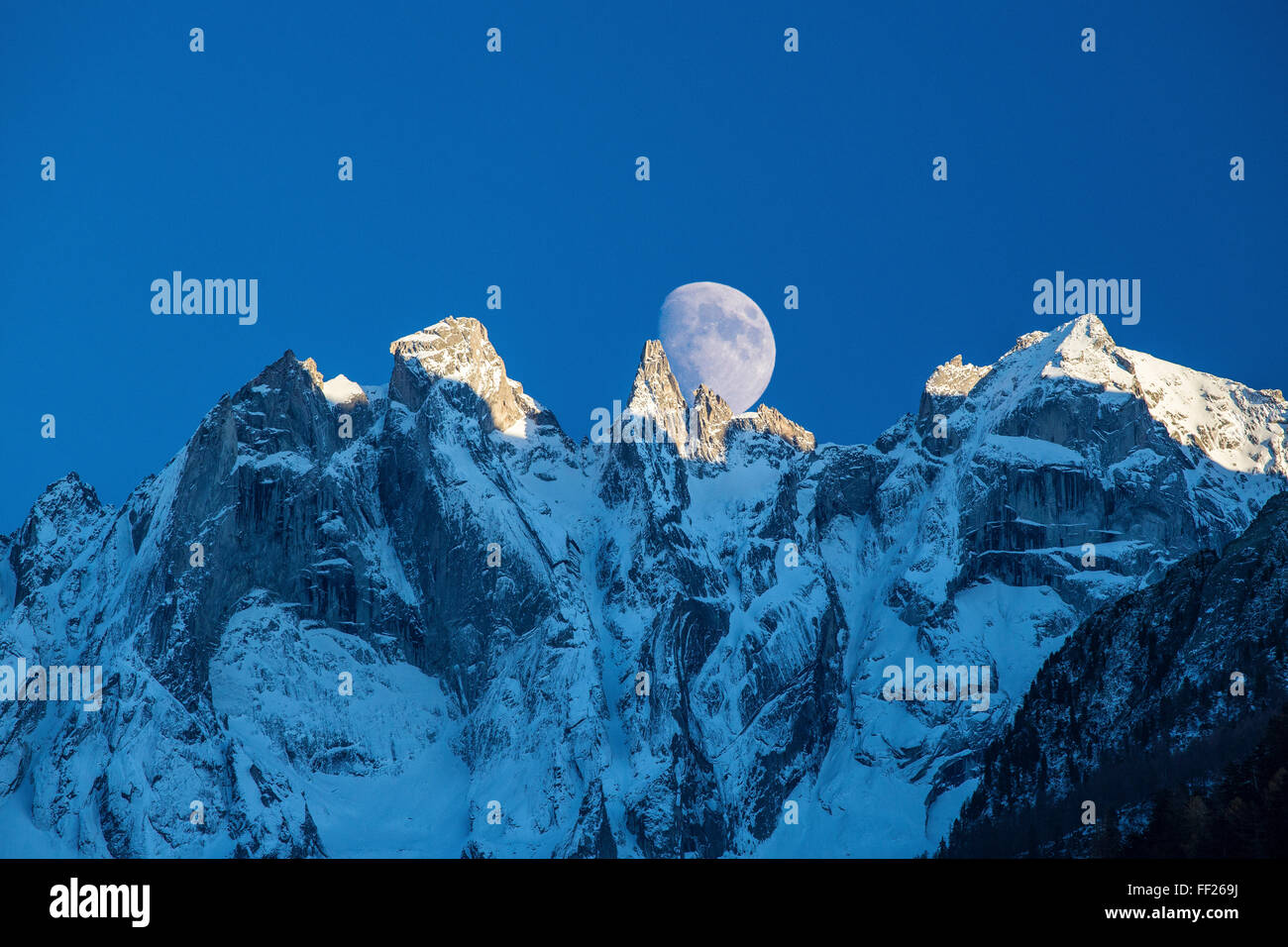 Der Mond erscheint hinter den schneebedeckten Bergen, beleuchten die Peaks bei Sonnenuntergang, Bondasca-Tal, Schweizer Alpen, Schweiz, Europa Stockfoto