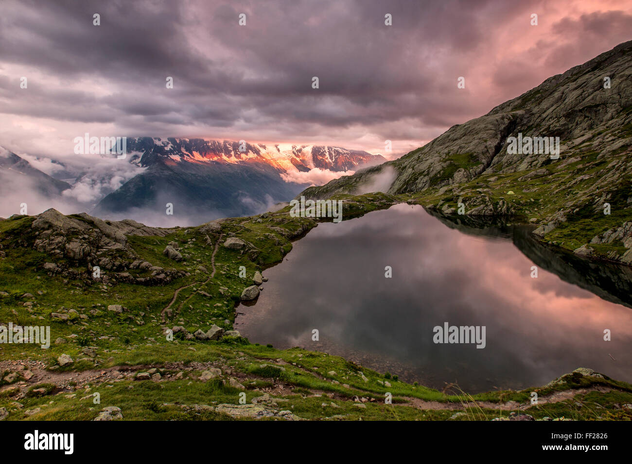 Wolken sind bei Sonnenuntergang am Lac de Cheserys, Chamonix, Haute Savoie, Französische Alpen, Frankreich, Europa mit lila gefärbt. Stockfoto