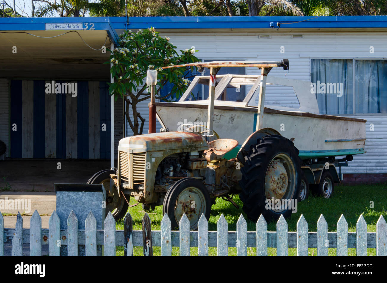 Ein alter Massey Ferguson Traktor und Boot im Vorgarten eines Cottage in Currarong an der Südküste von New South Wales in Australien Stockfoto