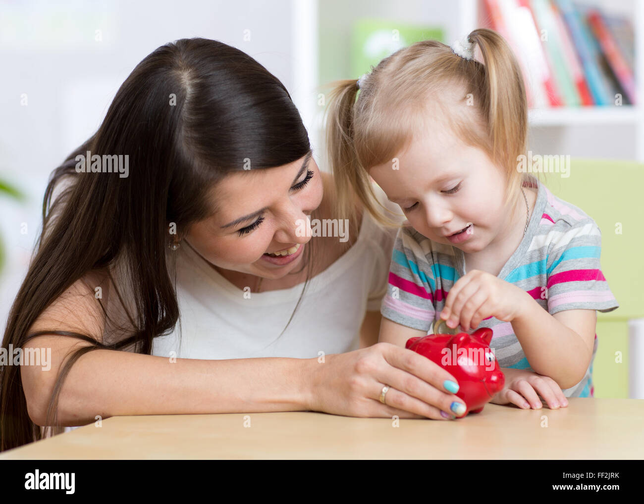 Mutter und Tochter Sparschwein Münzen Inbetriebnahme Stockfoto