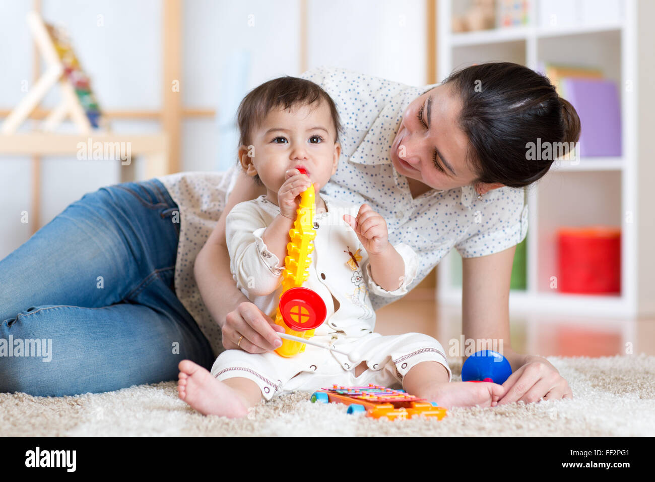Mama und Baby spielen musikalische Spielzeug zu Hause Stockfoto