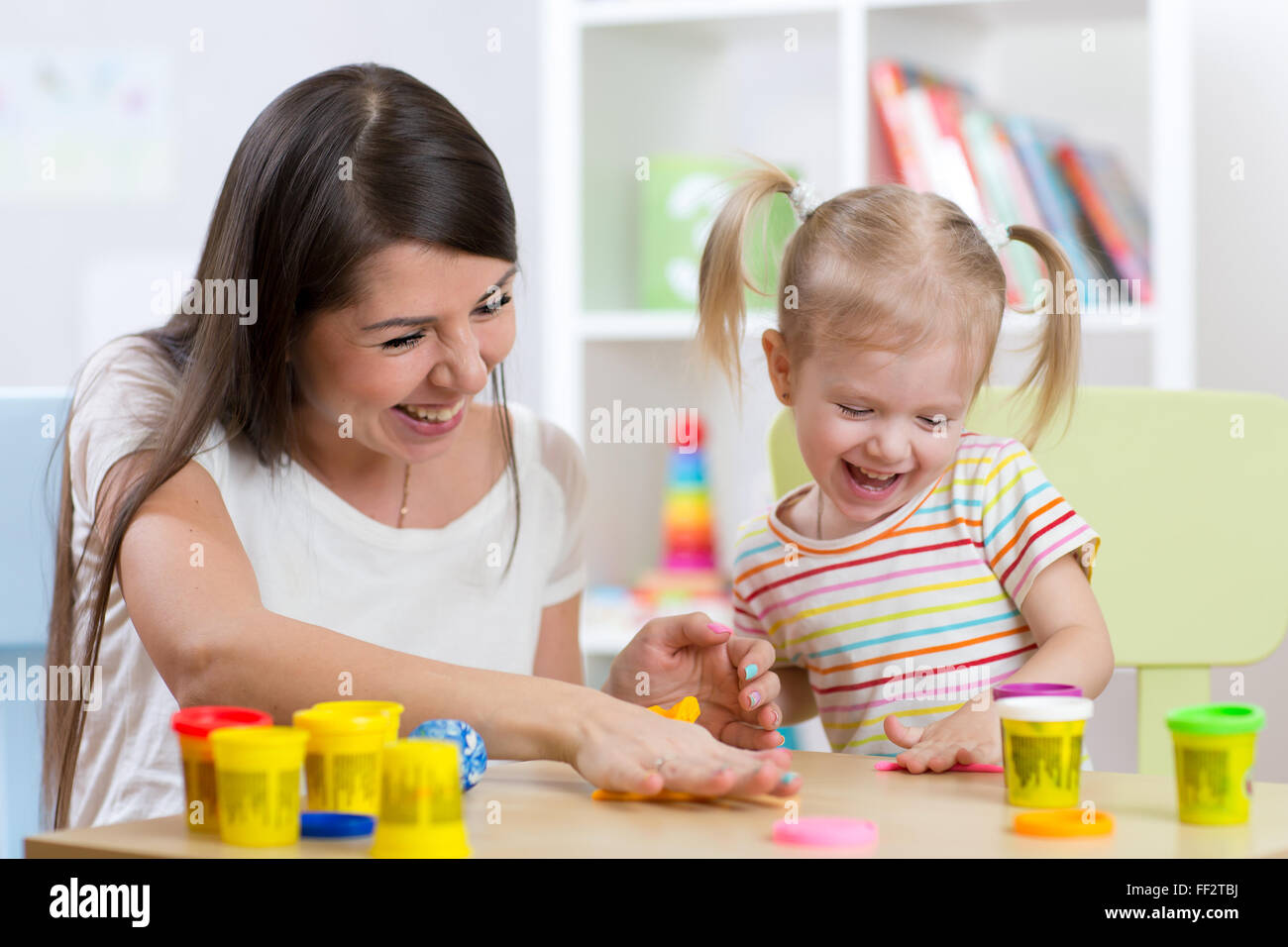 Junge hübsche Frau und Kind Mädchen spielen mit bunten Ton im Kindergarten Stockfoto