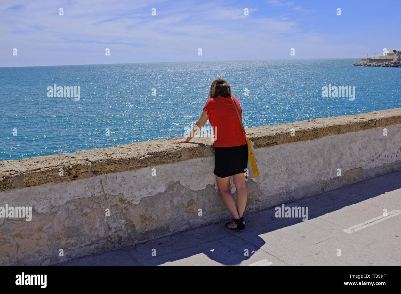 Eine Frau blickt auf das Meer am Strand in Cadiz, Spanien Stockfoto