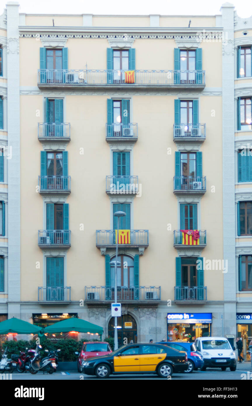 Fassade eines Gebäudes in Barcelona mit einem Taxi an die Tür und nationalistischen Fahnen auf den Balkonen Stockfoto