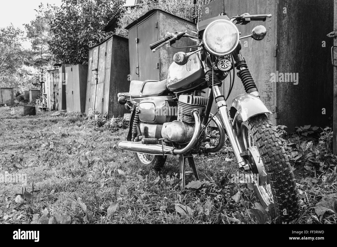 Altes Motorrad auf Grass Hof geparkt. Generische Oldtimer Motorrad Motorrad In Landschaft Stockfoto