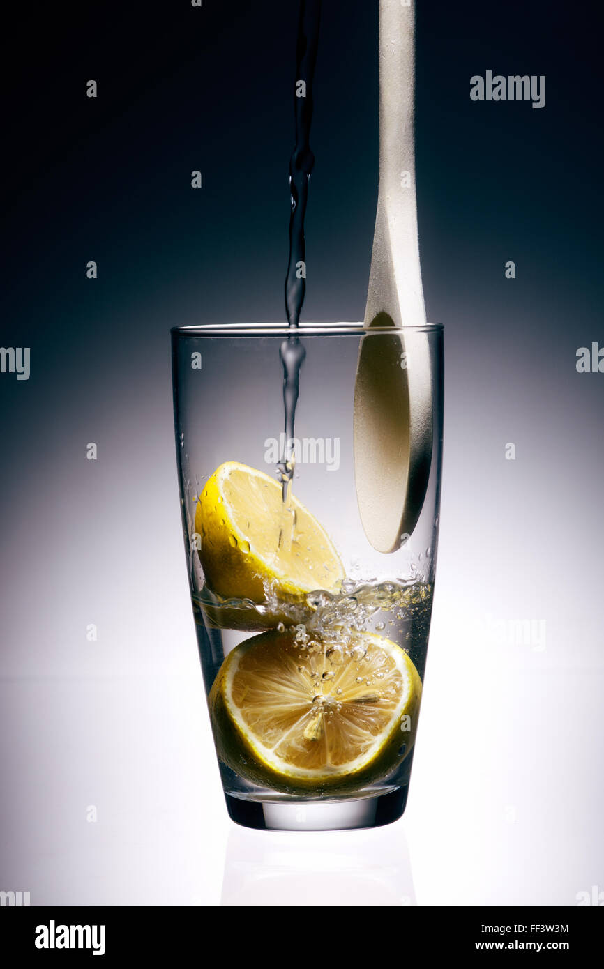 Wasser wird in einem Glas Zitronen gegossen Stockfoto