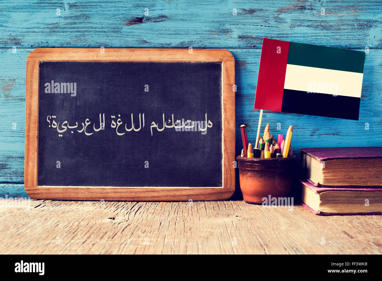 eine Tafel mit der Frage sprichst du Arabisch? geschrieben in Arabisch, einen Topf mit Bleistiften, einige Bücher und die Flagge der Vereinten Nationen Stockfoto