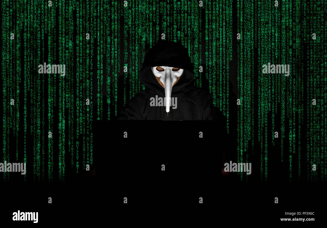 Ein maskierter Mann auf einen Laptop als Symbol für die Gefahren des Internets. Stockfoto