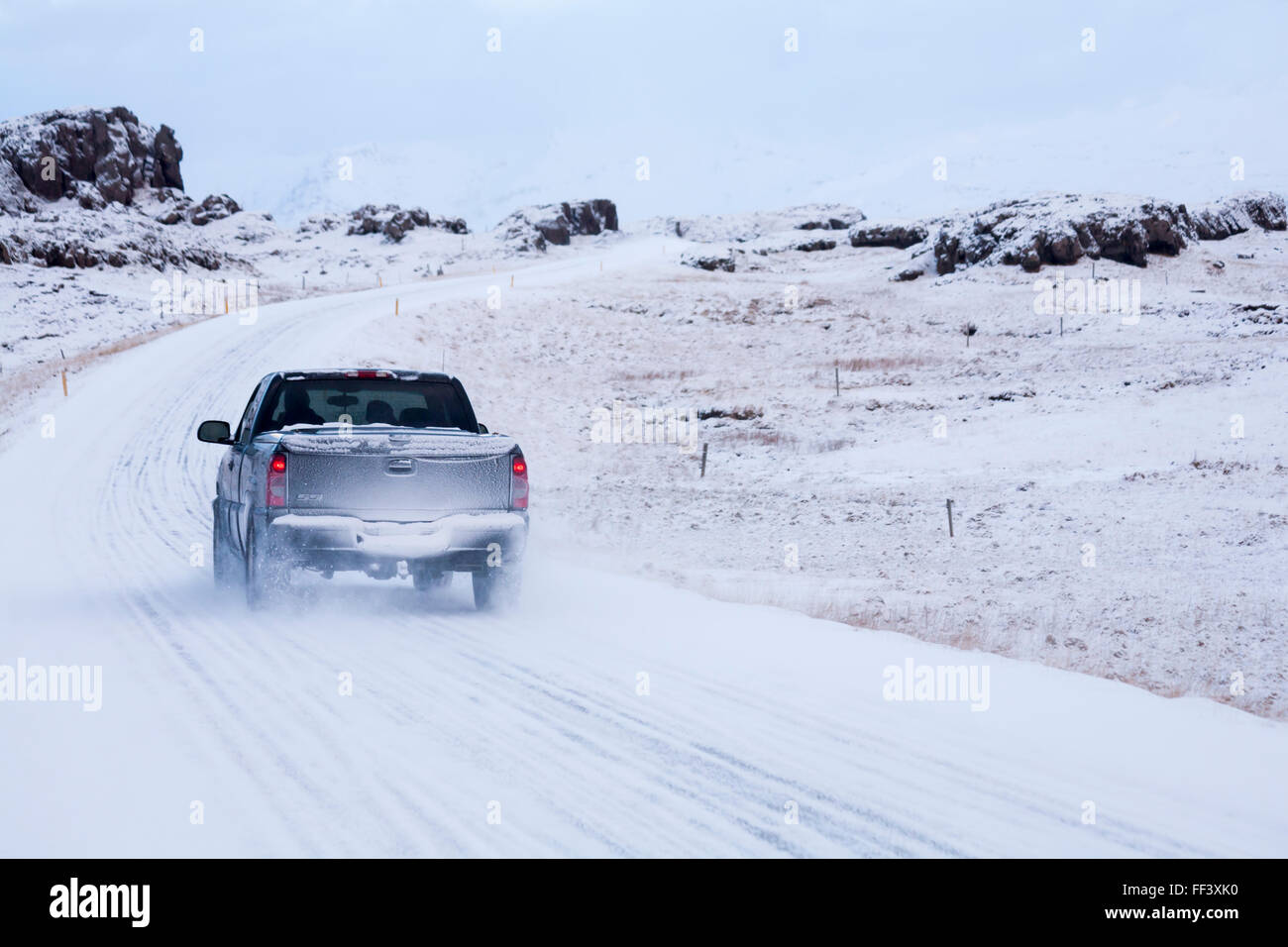Fahrzeug, Lkw abholen, Fahrt entlang der Straße durch schneebedeckte Berge in Island im Januar Stockfoto