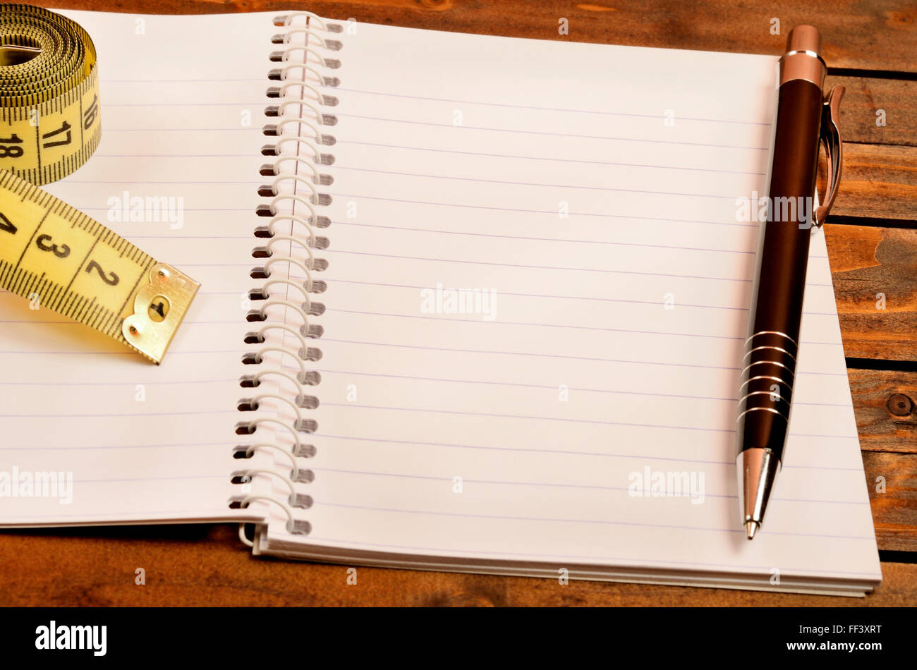 Notizblock mit Stift und Zentimeter auf Tisch Stockfoto