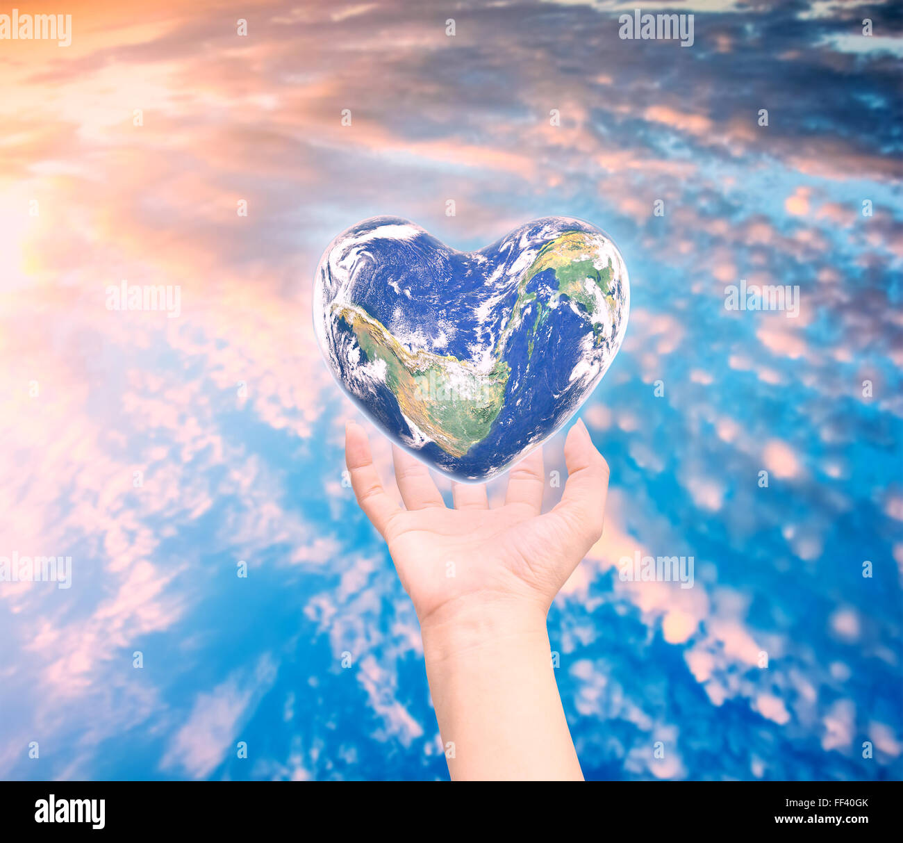 Welt in Herzform mit über Frauen, die menschlichen Hände auf unscharf natürlichen Hintergrund blau Cyan Türkis Baum und Himmel: Welt-Herz-Hea Stockfoto