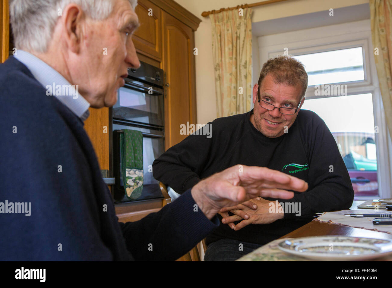Landwirt Howell Williams und Chris Blake die grünen Täler in der Bauernhof-Küche diskutieren die 15kW Mikro Wasserkraft-Generator zur Stromerzeugung auf der Abercrave Farm auf den Brecon Beacons, Wales sitzen. Stockfoto