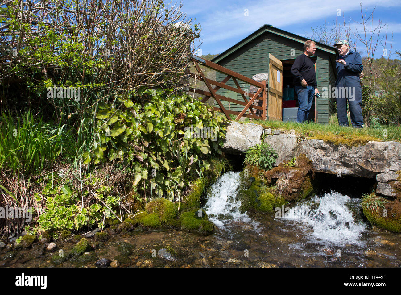 Walisische Schafzüchter stehen Howell Williams und Chris Blake die grünen Täler am Ufer des Baches an der Basis der Bauernhof 15kW Wasserkraftwerk auf der Brecon Beacons, Wales. Stockfoto