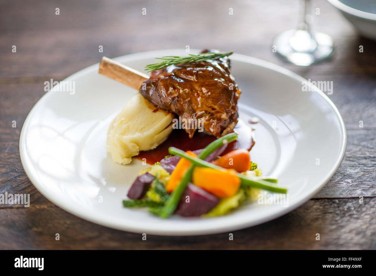 Eine Lammkeule mit Kartoffelpüree und Gemüse auf einem Teller Stockfoto