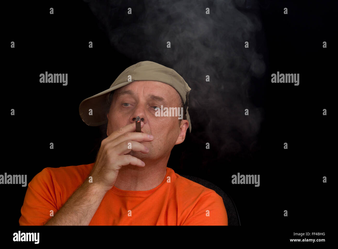 Indoor-Porträt von reifen Mann mit Baseballmütze und rauchende Zigarre Stockfoto