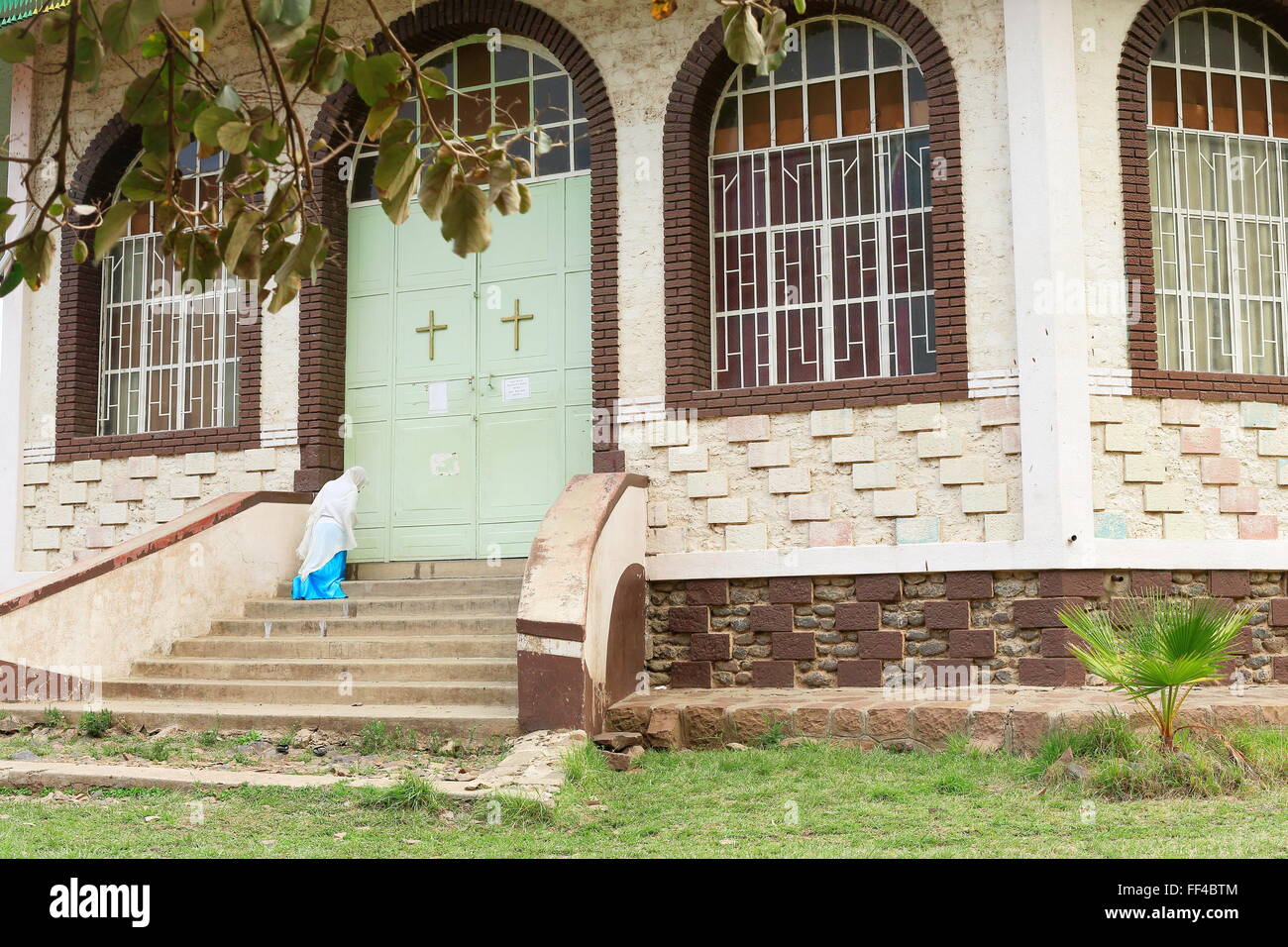 Anhänger-Frau auf eine Treppe, die zu dem geschlossenen Tor Bete Gebriel-St.Gabriel orthodoxen christlichen Kirche beten. Kombolcha Stockfoto