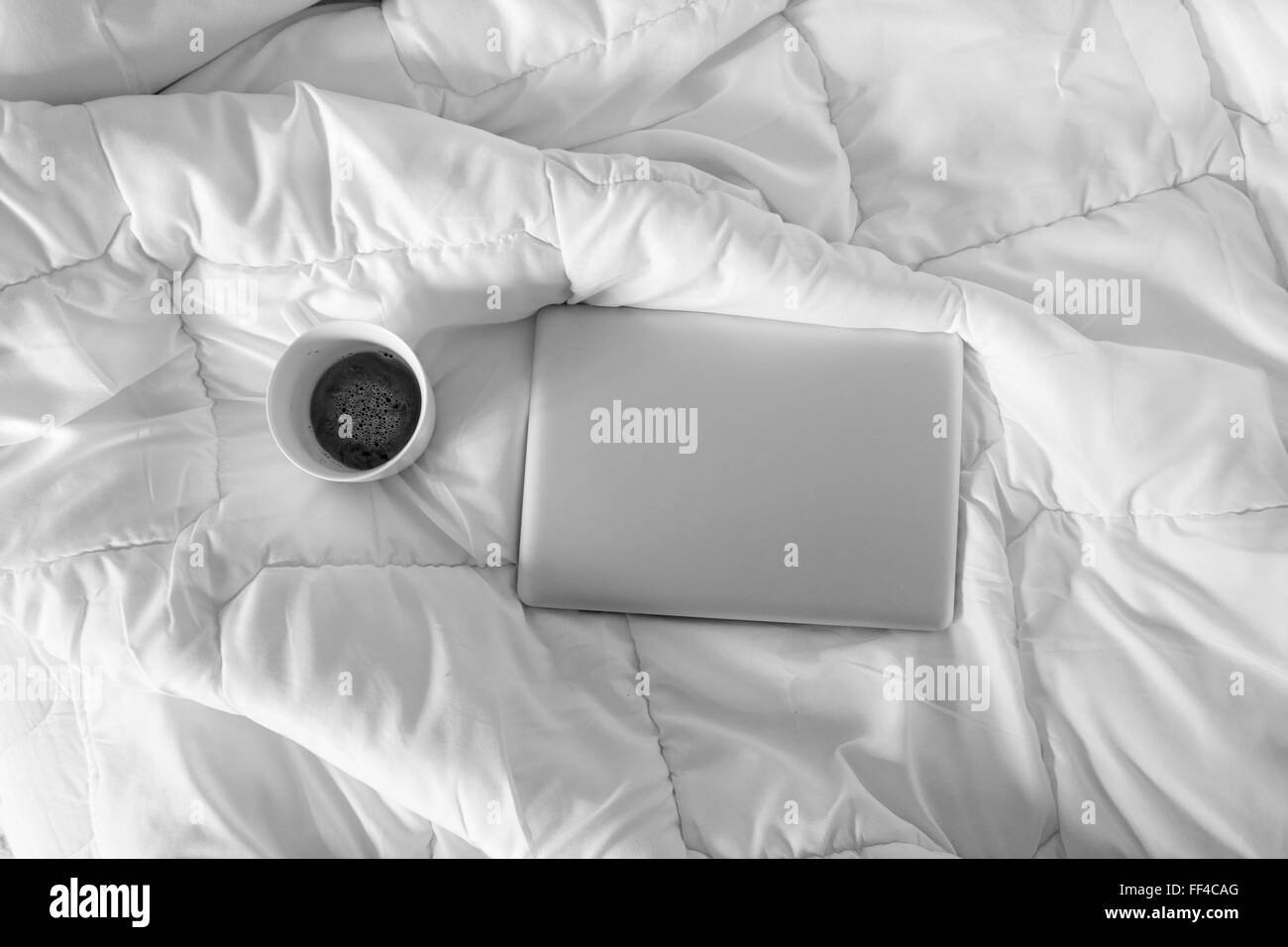 Arbeiten im Bett, Laptop und weißen Tasse Kaffee auf weißen Bett, Morgenlicht Stockfoto