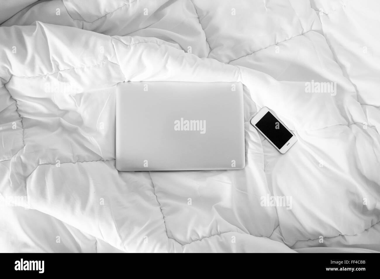 Arbeiten im Bett, Laptop und Smartphone auf weißen Bett, Morgenlicht Stockfoto
