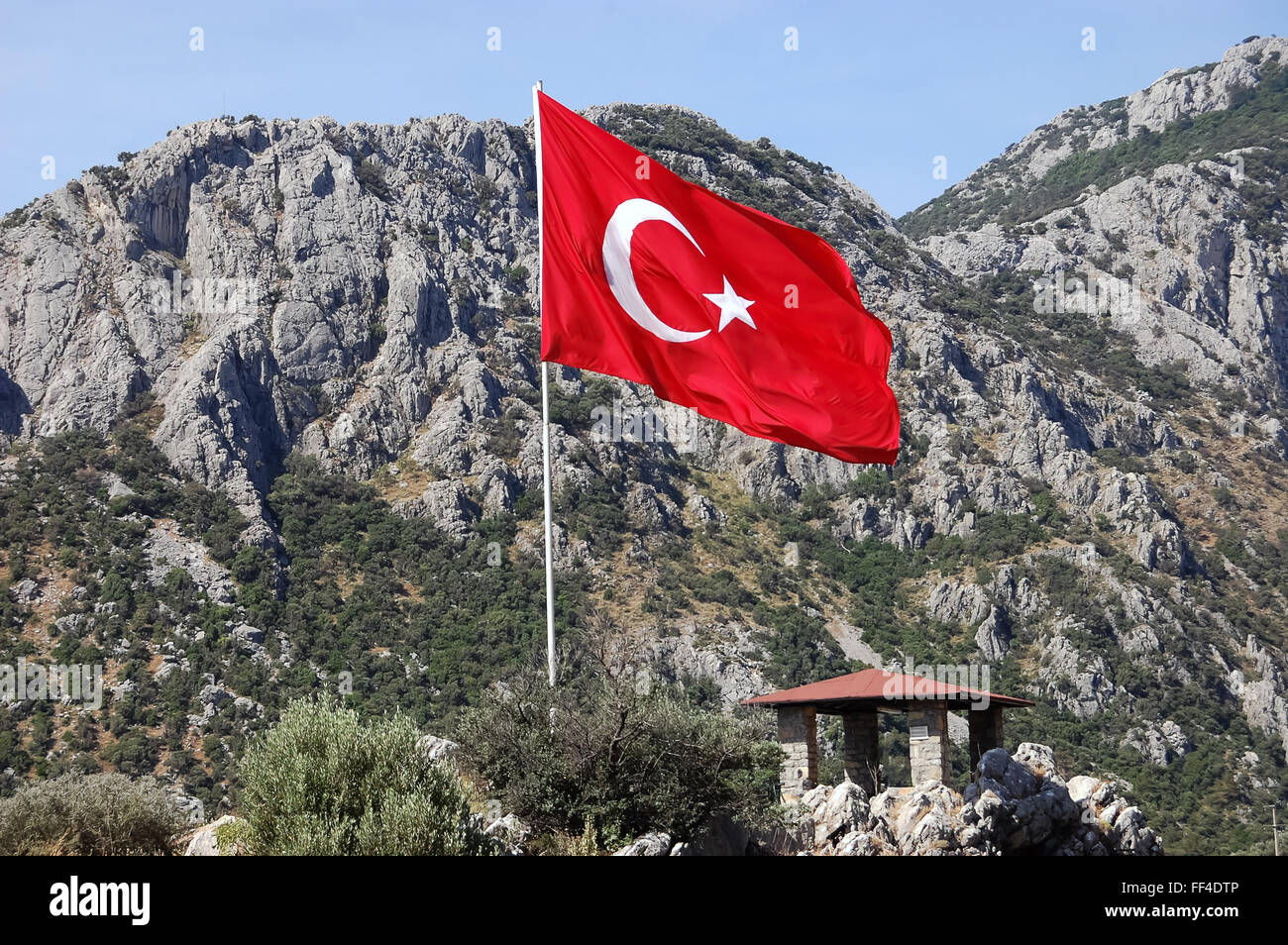 Winken die türkische Fahne in den Wind auf dem Hintergrund der Berge. Stockfoto