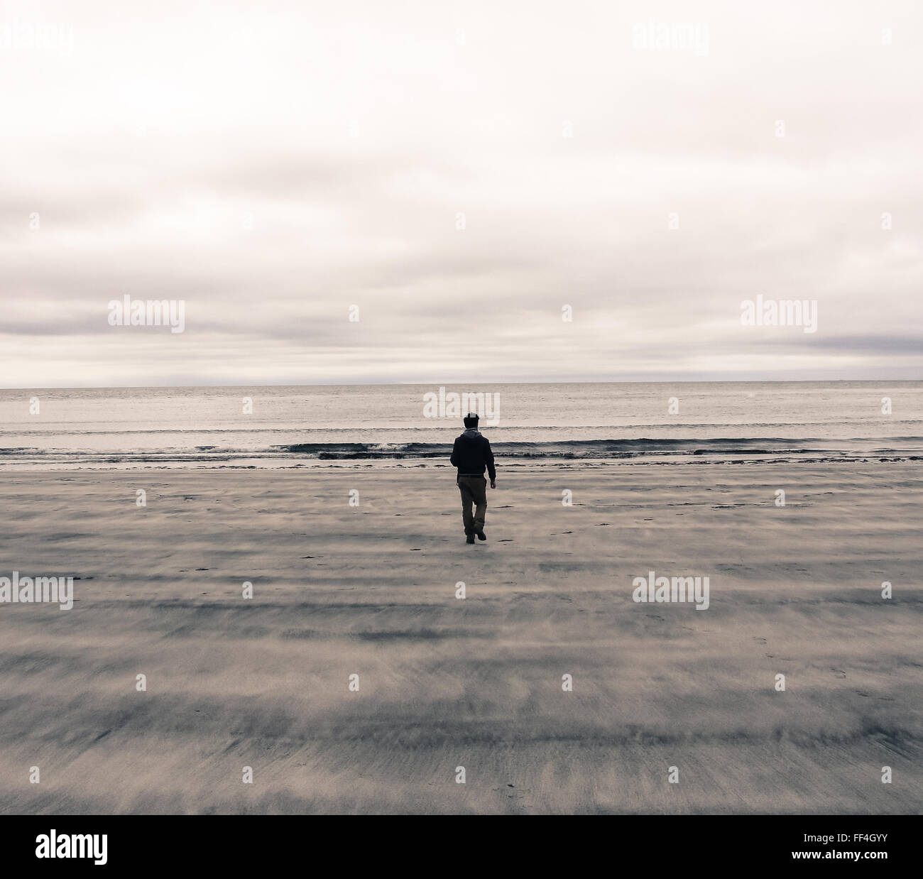 Bild von einem Mann von hinten zu Fuß auf einem Strand in Schottland (Vereinigtes Königreich). Polaroid Wirkung Stockfoto