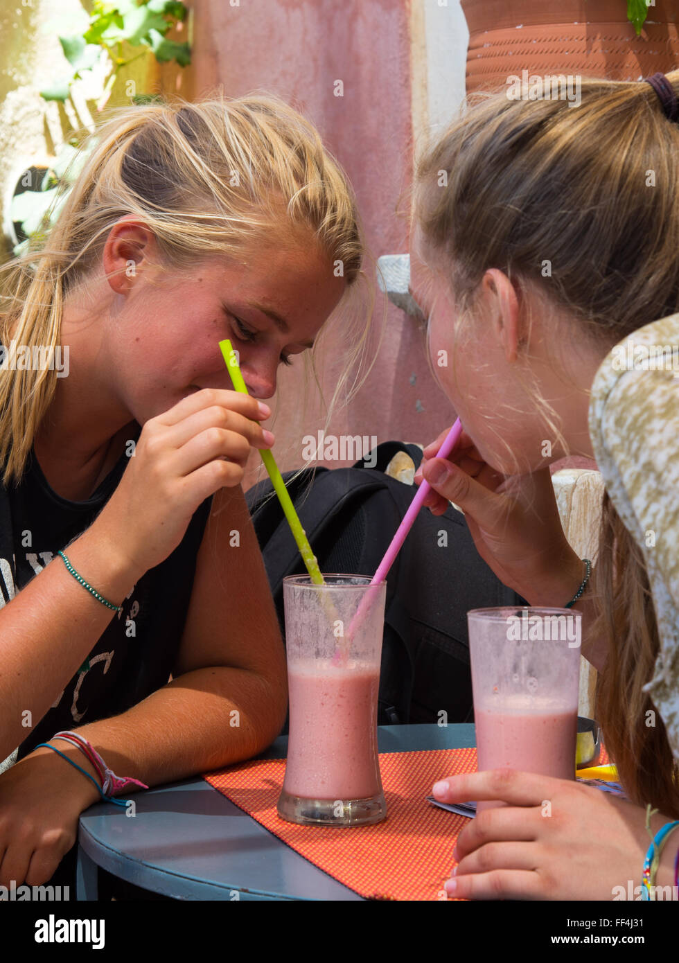 zwei Mädchen, trinken aus einem Glas Stockfoto