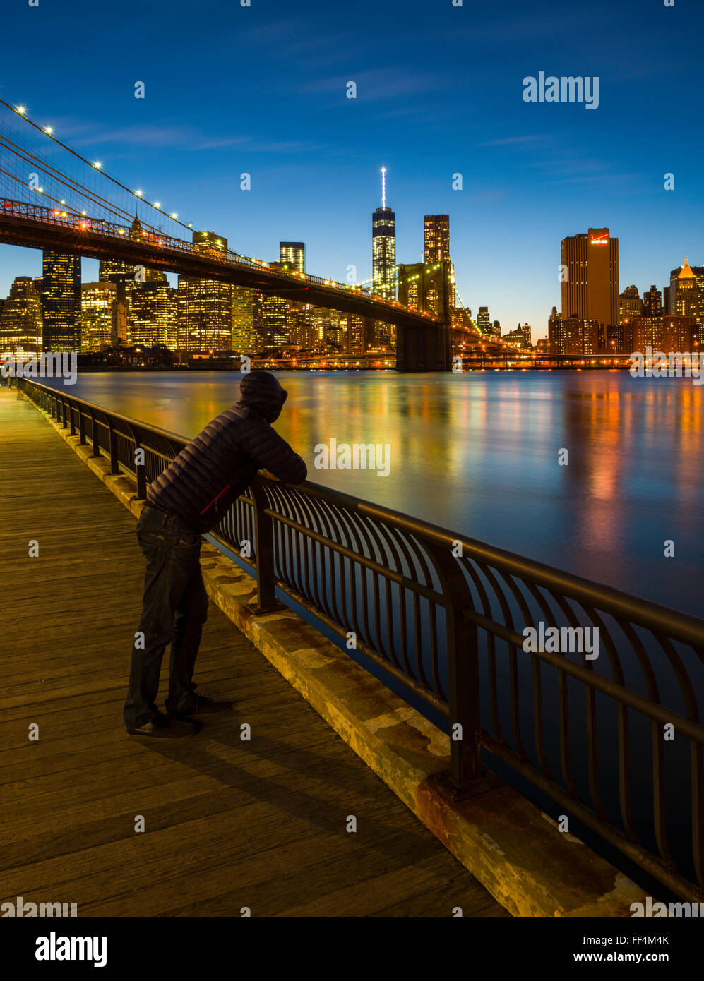 Mann, Blick auf Lower Manhattan und Brooklyn Bridge über den East River aus Brooklyn in der Abenddämmerung, New York City, New York, USA Stockfoto