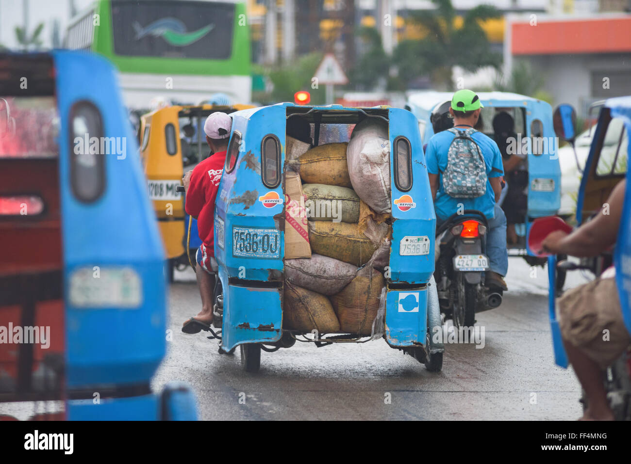 Cyclo Sackleinen Säcke in einer verregneten Straße mit starkem Verkehr in General Santos City, South Cotabato, der philippinischen transport eingesetzt Stockfoto