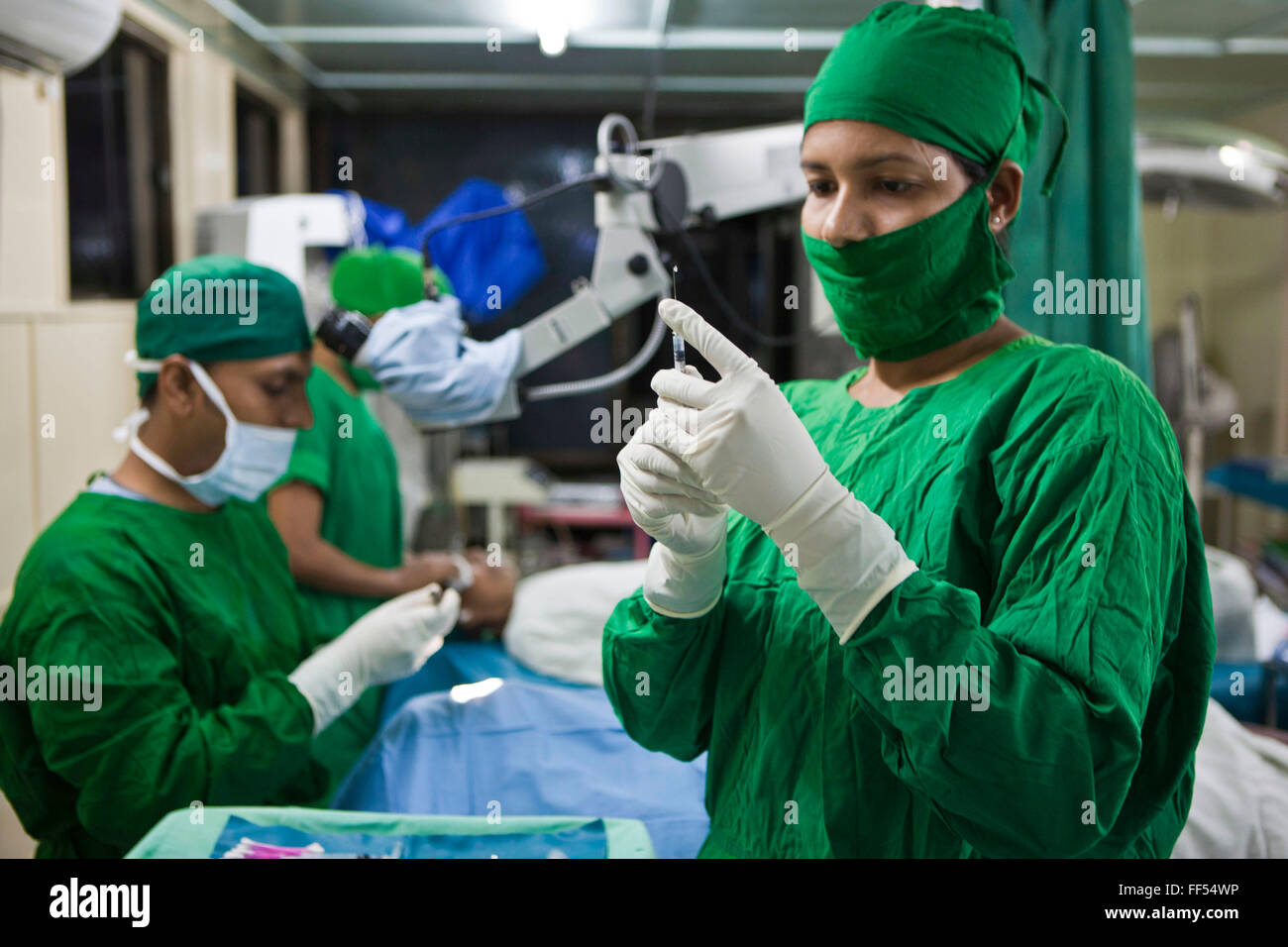 Eine Krankenschwester bereitet eine Nadel für Dr. Mohamed Shaheen auszuführenden Katarakt Operation an einem Patienten auf dem IFB Jibon Tari schwimmenden Krankenhaus, an den Ufern des Flusses Modhumoti vertäut.  Die Jibon Tari bewegt sich normalerweise Lage alle 3 Monate zu abgelegenen Fluss- und Offshore-Gebieten. Es wurde im Jahr 1999 ins Leben gerufen und hat großen Erfolg, dass 200.000 Menschen mehr zu erreichen.   Auswirkungen Gründung Bangladesch (IFB) bieten Betreuung, Unterstützung und Behandlung für Menschen mit Behinderungen in Bangladesch. Stockfoto