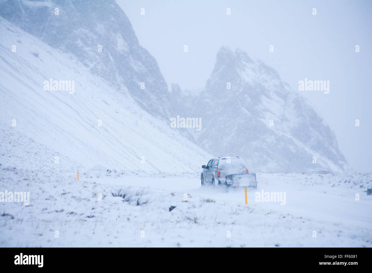 Ein Abschleppen des Fahrzeugs Anhänger fahren entlang der Straße durch schneebedeckte Berge in Island im Januar - schlechte Sicht schwierigen Fahrsituationen Stockfoto