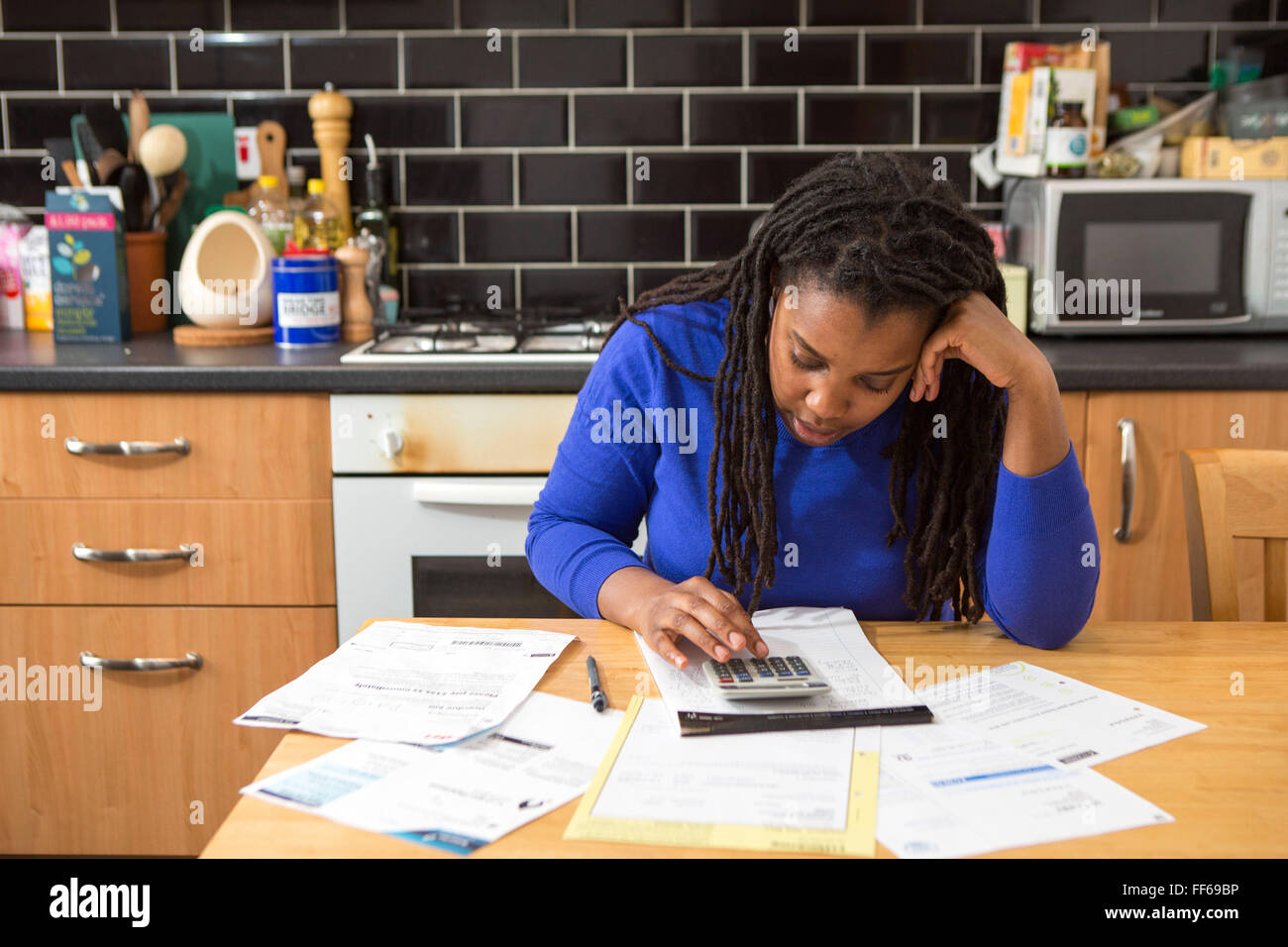 Eine junge Frau sitzt an ihrem Küchentisch zu Hause überprüfen über die Haushaltsrechnungen. Umgang mit Schulden. Haushalt Stromrechnungen, so dass es schwierig für eine britische Eigenheimzulage zu leisten. Schwierigkeiten Gas- und Stromrechnungen zu bezahlen ist üblich, da der wirtschaftliche Abschwung persönliche Finanzen spüren macht. London, UK. Stockfoto