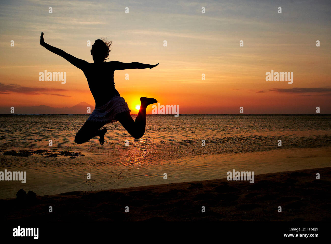 Silhouette einer Frau, die einen Sprung in der Luft, vor einem Sonnenuntergang Himmel gesehen. Stockfoto