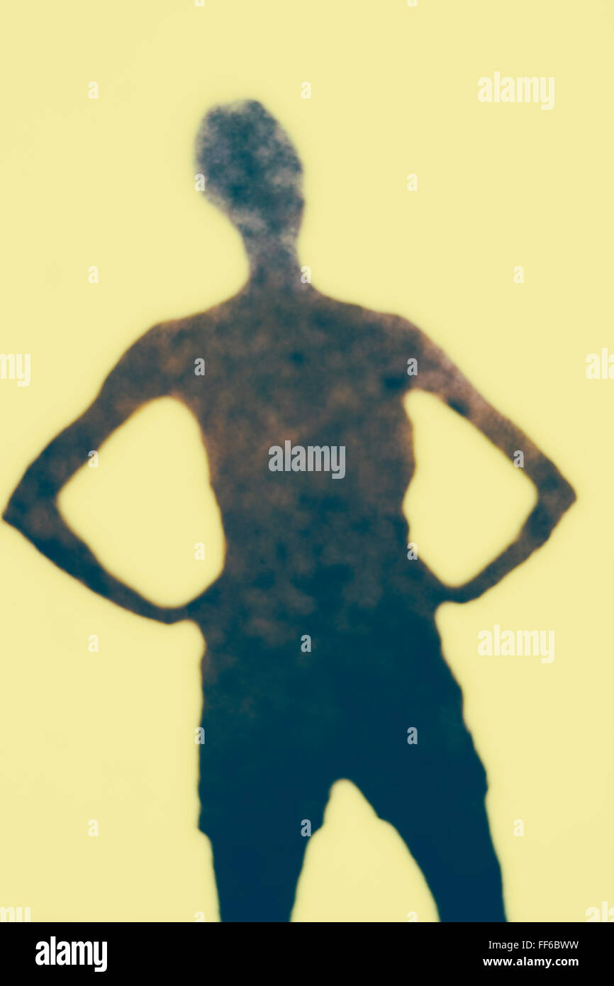 Die Umrisse eines menschlichen Körpers, ein Schatten vor einem einfarbigen Hintergrund. Stockfoto