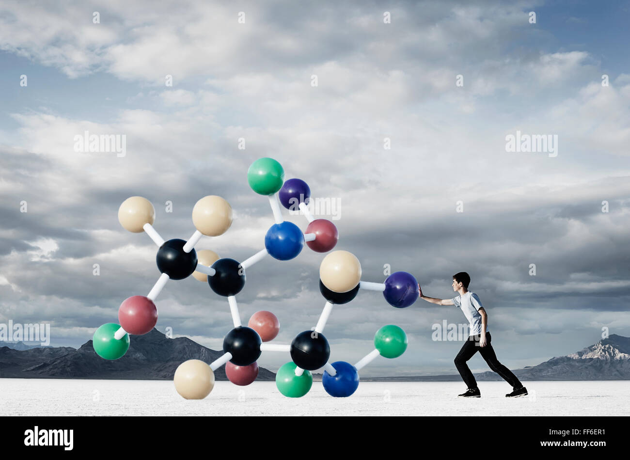 Ein Teenager, legte seine Hand heraus, um eine große strukturelle Molekülmodell von ihm Weg zu drücken. Stockfoto
