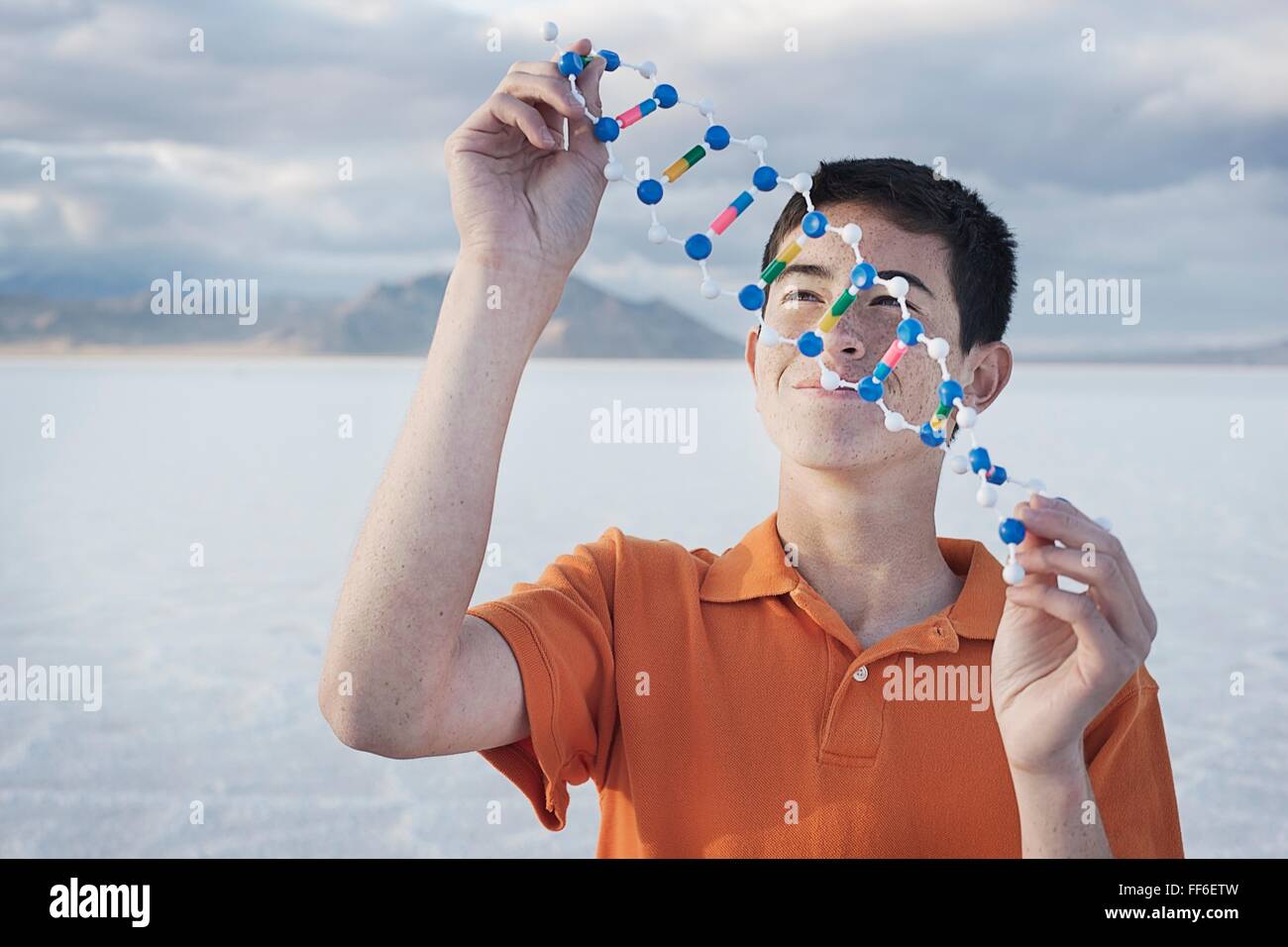 Ein Teenager in eine orange Polo-Shirt, eine molekulare Struktur-Modell hält und es untersuchen. Stockfoto