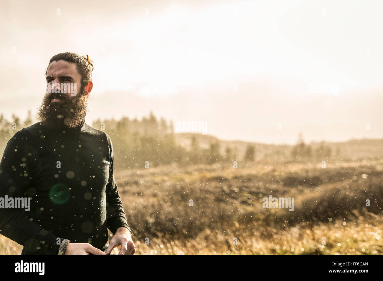 Ein Mann steht im lichtdurchfluteten offenen Land im Winter. Stockfoto