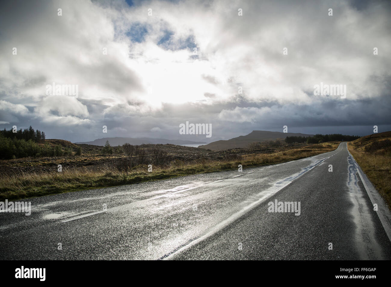Eine leere zweispurige Straße durch eine verlassene Landschaft, in die Ferne zu erreichen. Niedrige Wolke am Himmel. Stockfoto
