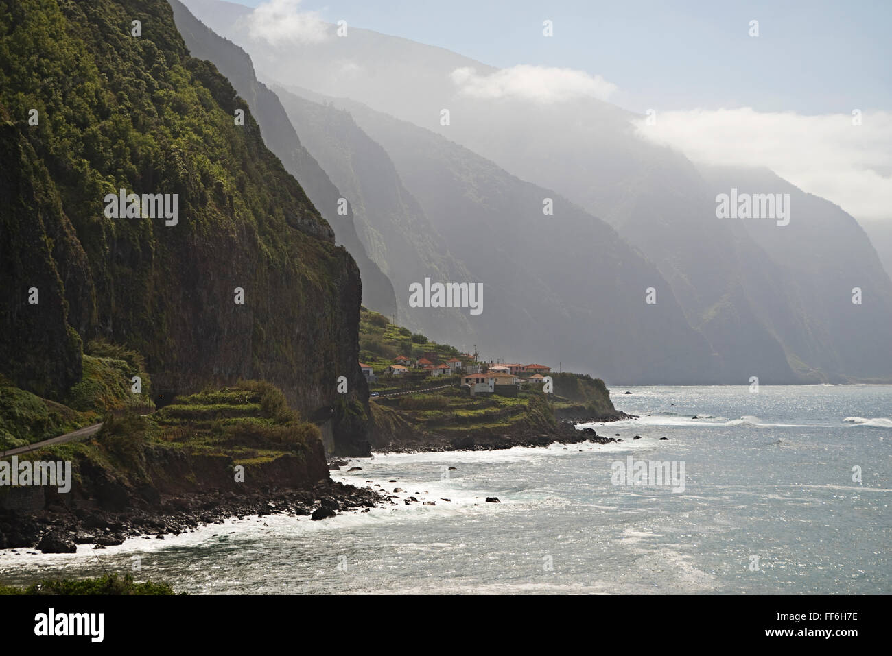 Eine schmale Küstenstraße schlängelt sich entlang der Klippen, Bergketten und abgelegene Dörfer in der Nähe von Ponta Delgada, Nordküste von Madeira Stockfoto