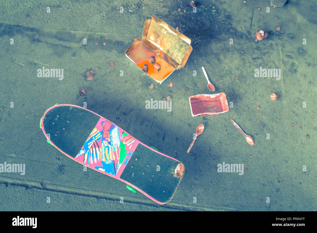 Skateboard und leere Eisbox, Löffel und schokoladeüberzogenen Marshmallow Leckereien Stockfoto