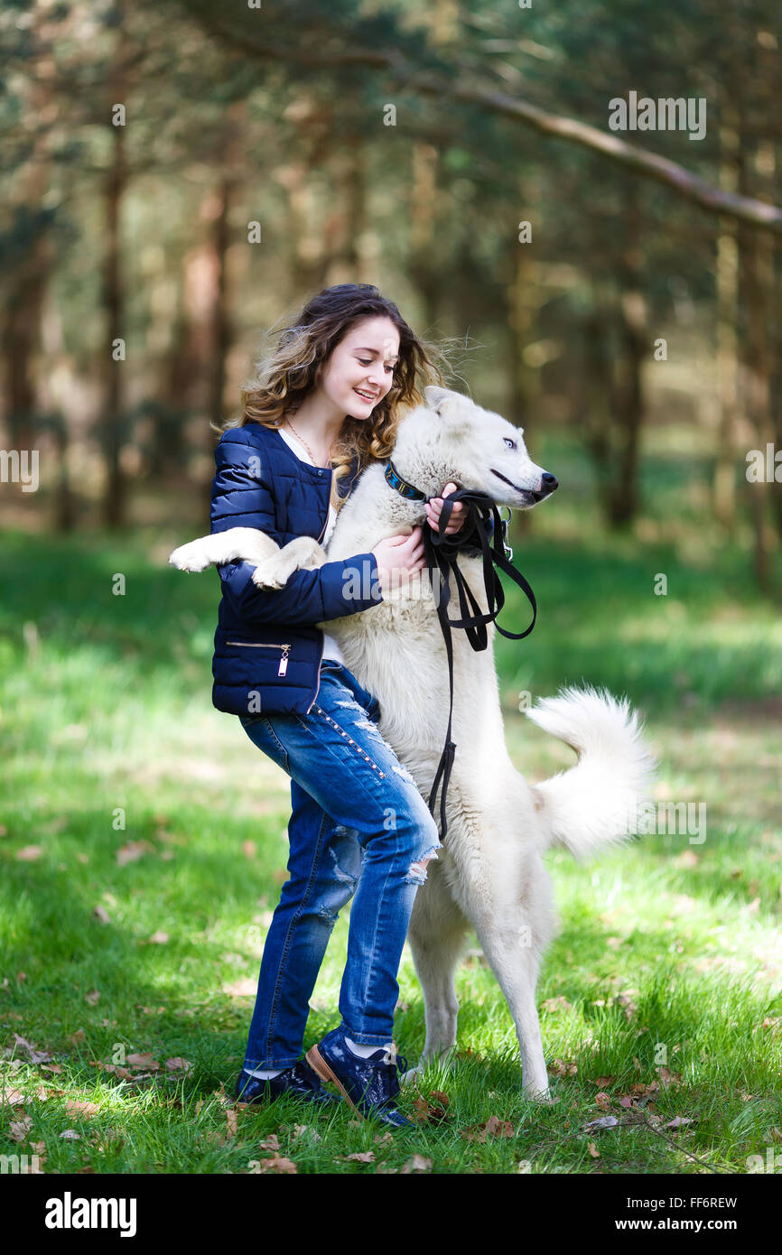 Fröhliches junges Mädchen umarmen husky Hund in einem Wald im Frühjahr Stockfoto
