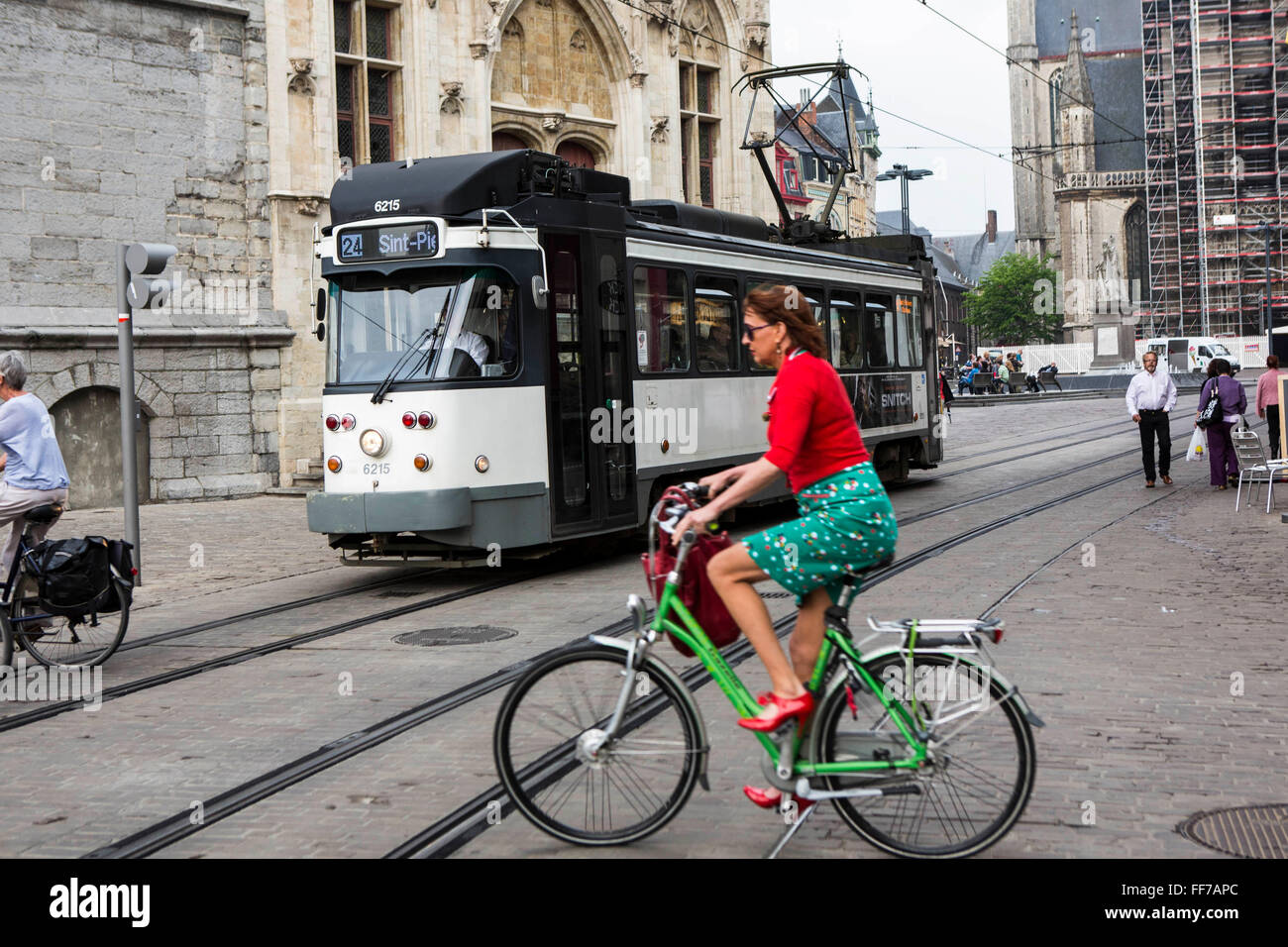 Eine weibliche belgischen Radsportler Fahrten mit dem Fahrrad über  Straßenbahn-Linien des Straßenbahnnetzes Ghent in Gent, Belgien. Eine alte  Straßenbahn fährt vorbei in den Hintergrund Stockfotografie - Alamy