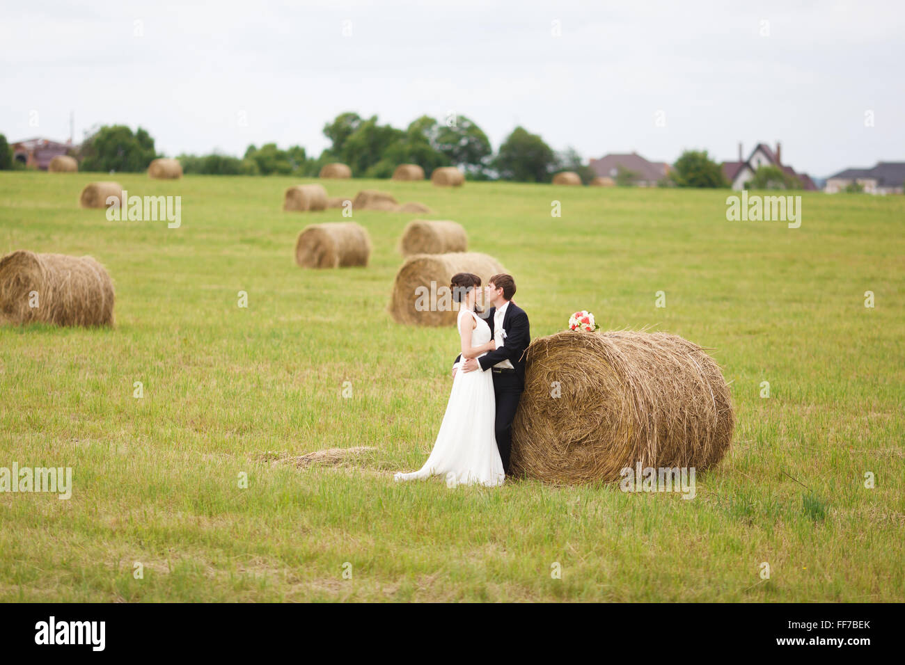 Braut und Bräutigam in der Nähe von Heu auf einem ländlichen Gebiet Stockfoto
