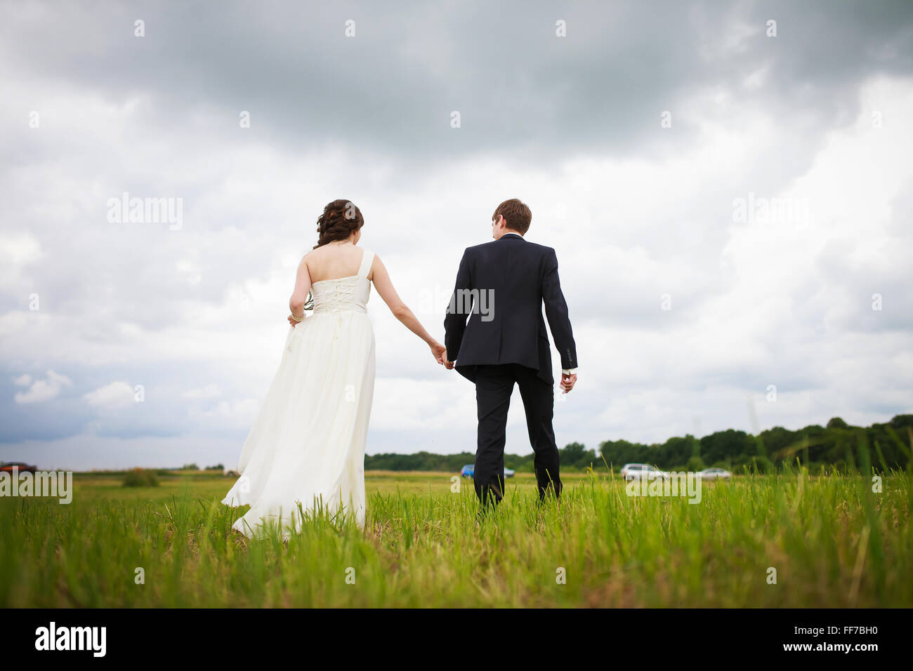 Die Braut und Bräutigam auf dem Feld weggehen Stockfoto