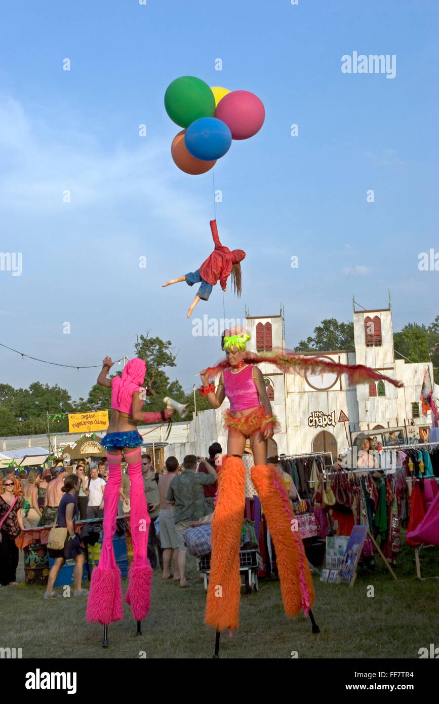Zwei Stelzenläufer Künstler und der Künstler Bansky, mit seinem Markenzeichen-Mädchen mit Luftballons, gehen vorbei an der Kapelle der Liebe & Schrecken in verloren Unbestimmtheit auf dem Glastonbury Festival. Stockfoto
