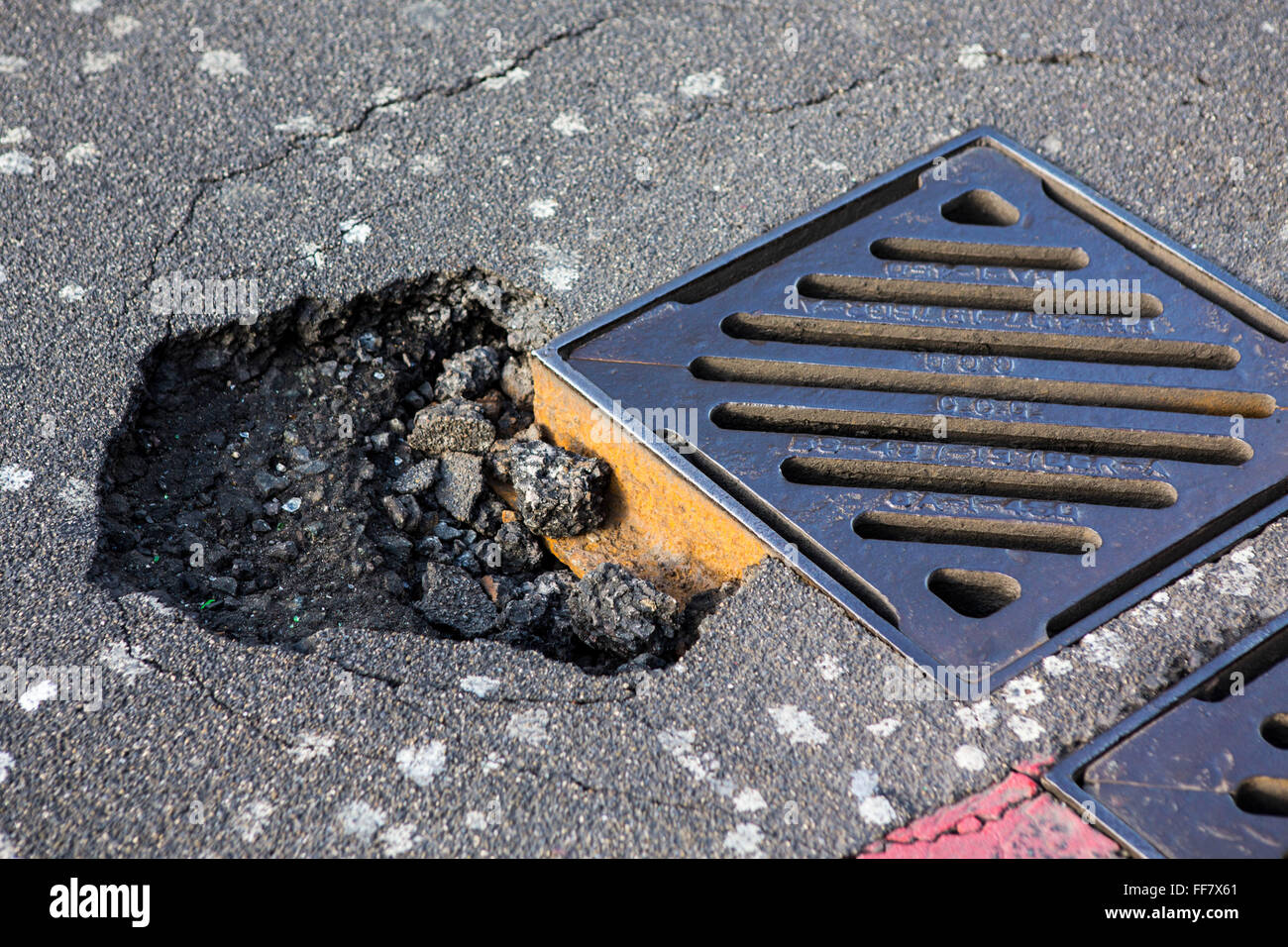 Eine große Straße Schlagloch am Rande eine Drainage Rost in Hackney, London, Vereinigtes Königreich.  Die Verantwortung für die Aufrechterhaltung der sicheren Straßenbeläge liegt mit den lokalen Behörden, wie Hackney Rat. Stockfoto