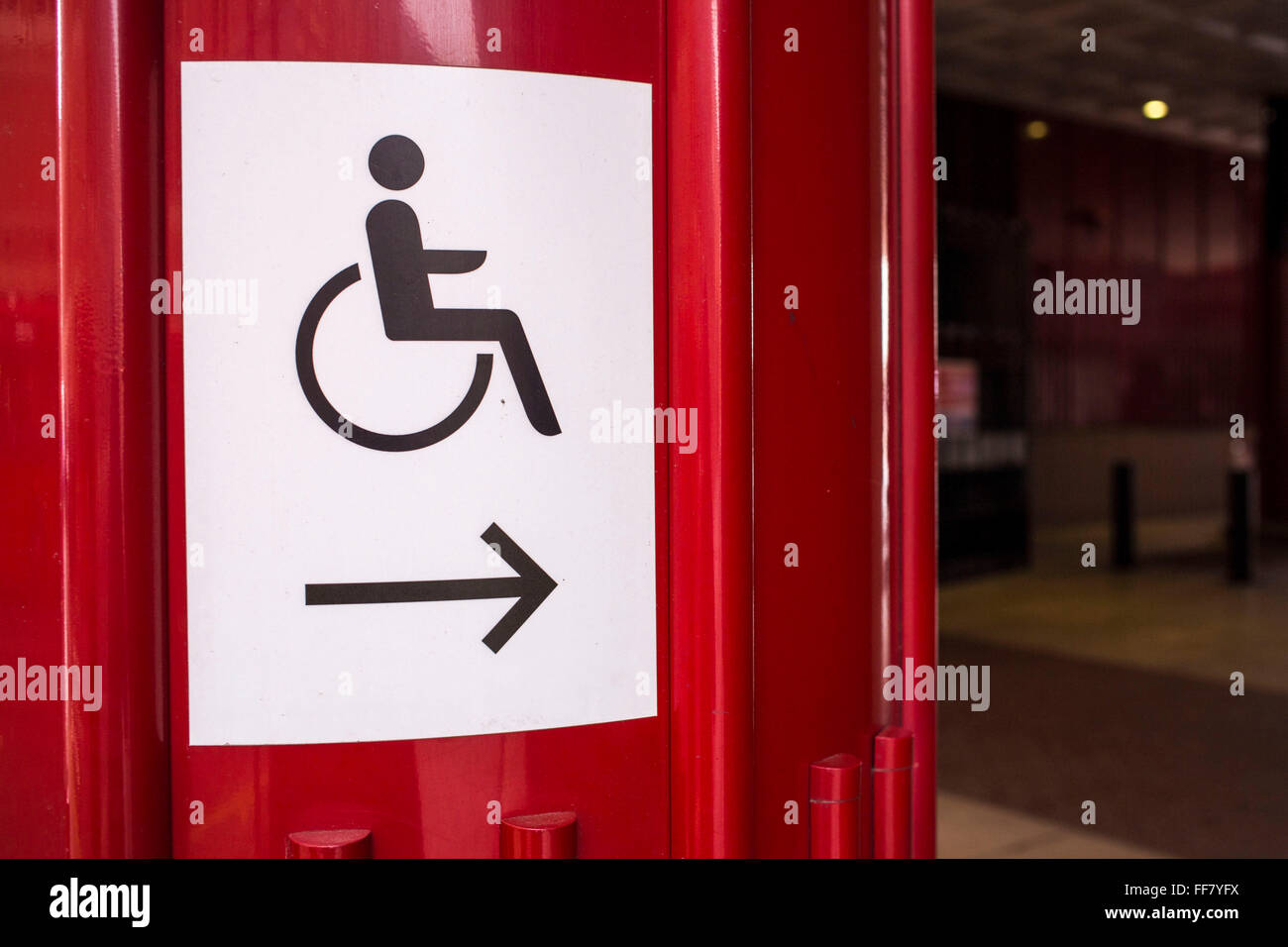 Ein Schild zeigt den Weg für Menschen mit eingeschränkter Mobilität in der British Library in London, Vereinigtes Königreich.  Die Zeichen nutzen Sie den internationalen Symbol Zugang in 1968 entworfen. Das Symbol wird häufig gesehen, wo Zugang verbessert wurde, insbesondere für Rollstuhlfahrer, sondern auch für andere Behindertenfragen.  Das Symbol kennzeichnet häufig, die Entfernung von umweltbedingten Barrieren, wie z. B. Schritte, um auch ältere Menschen, Eltern mit Kinderwagen und Reisenden helfen. Stockfoto