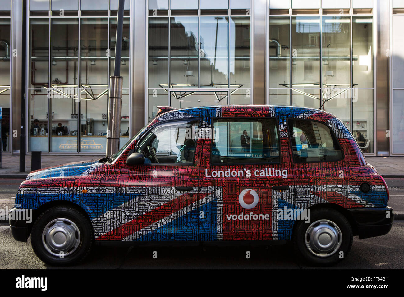 Ein traditionelles London Hackney Beförderung Taxi Werbung von Vodafone, einem multi-nationalen Mobilfunkgeschäft. Stockfoto