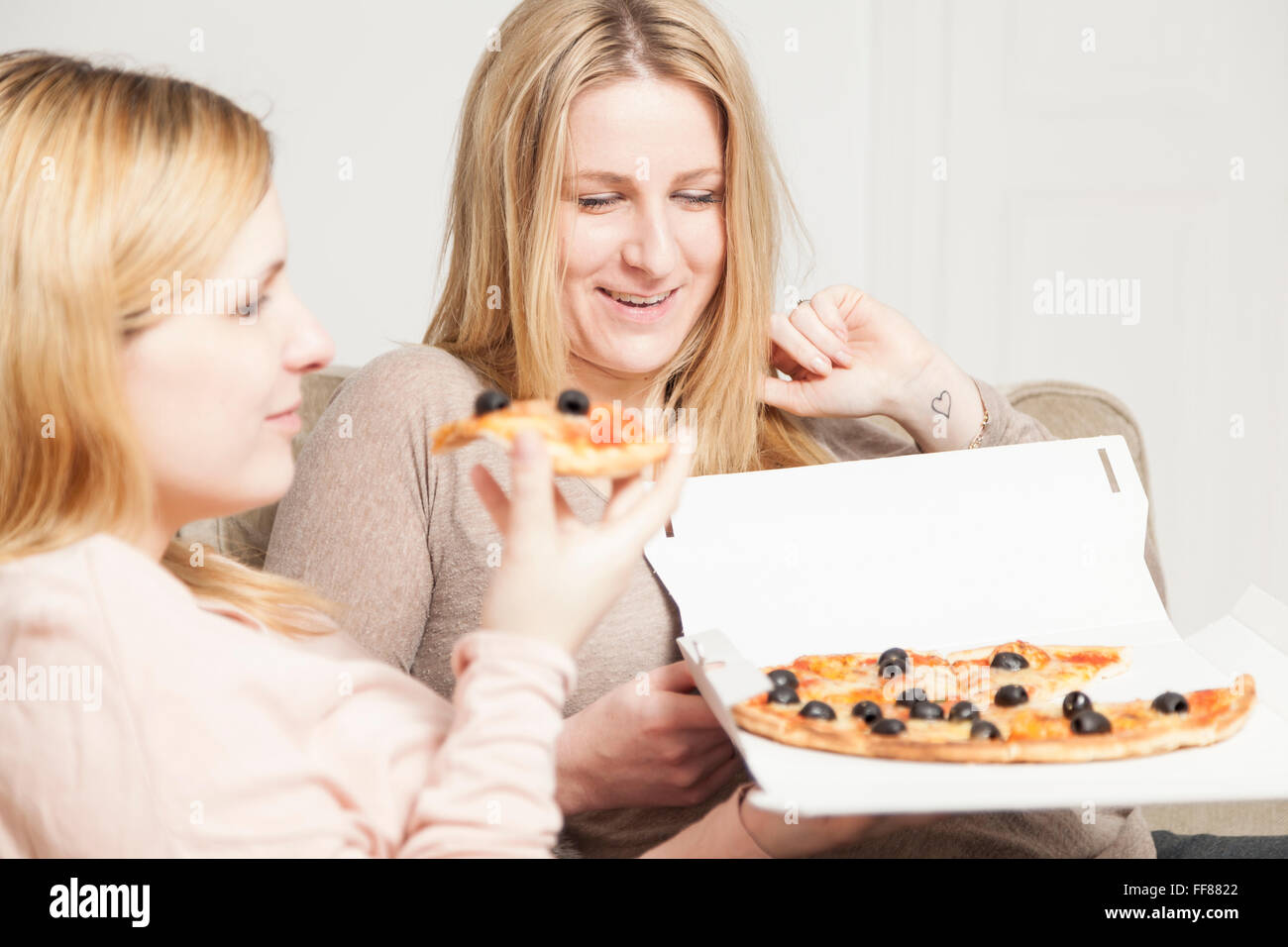 Freundinnen, die Pizza zu Hause essen Stockfoto